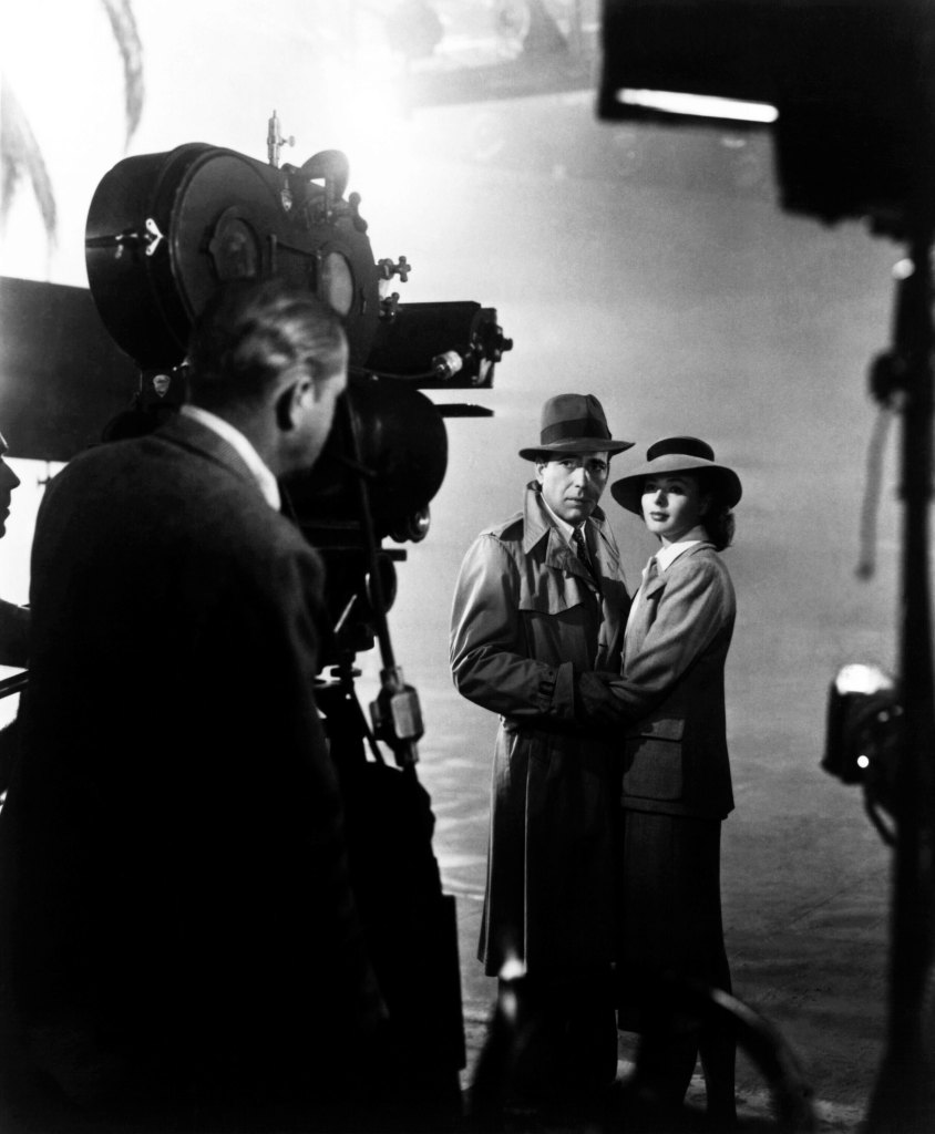 CASABLANCA, Michael Curtiz directs Humphrey Bogart and Ingrid Bergman filming on set, 1942