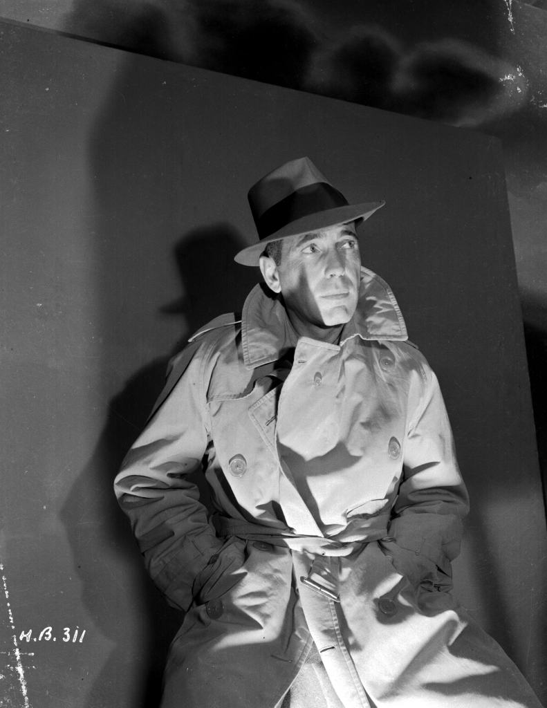 Headshot of actor Humphrey Bogart (1899-1957), wearing hat and trench coat, for Warner Bros Studios, 1942