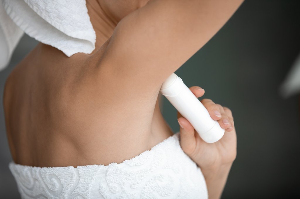 Woman applying deodorant to her underarms