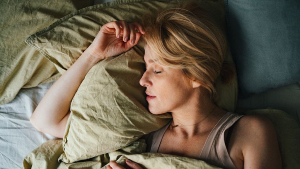 mature woman sleeping well in bed with her eyes closed on a pillow, one of the benefits of reading