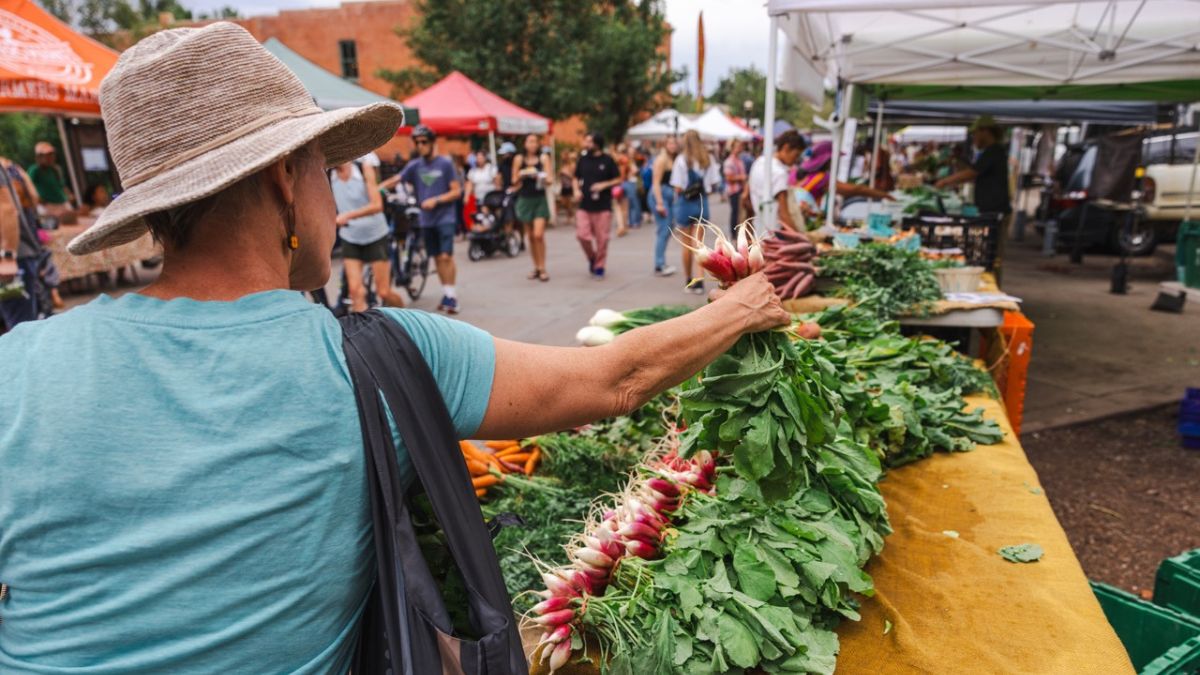 mature woman shopping at her local farmers market to enjoy health and community benefits