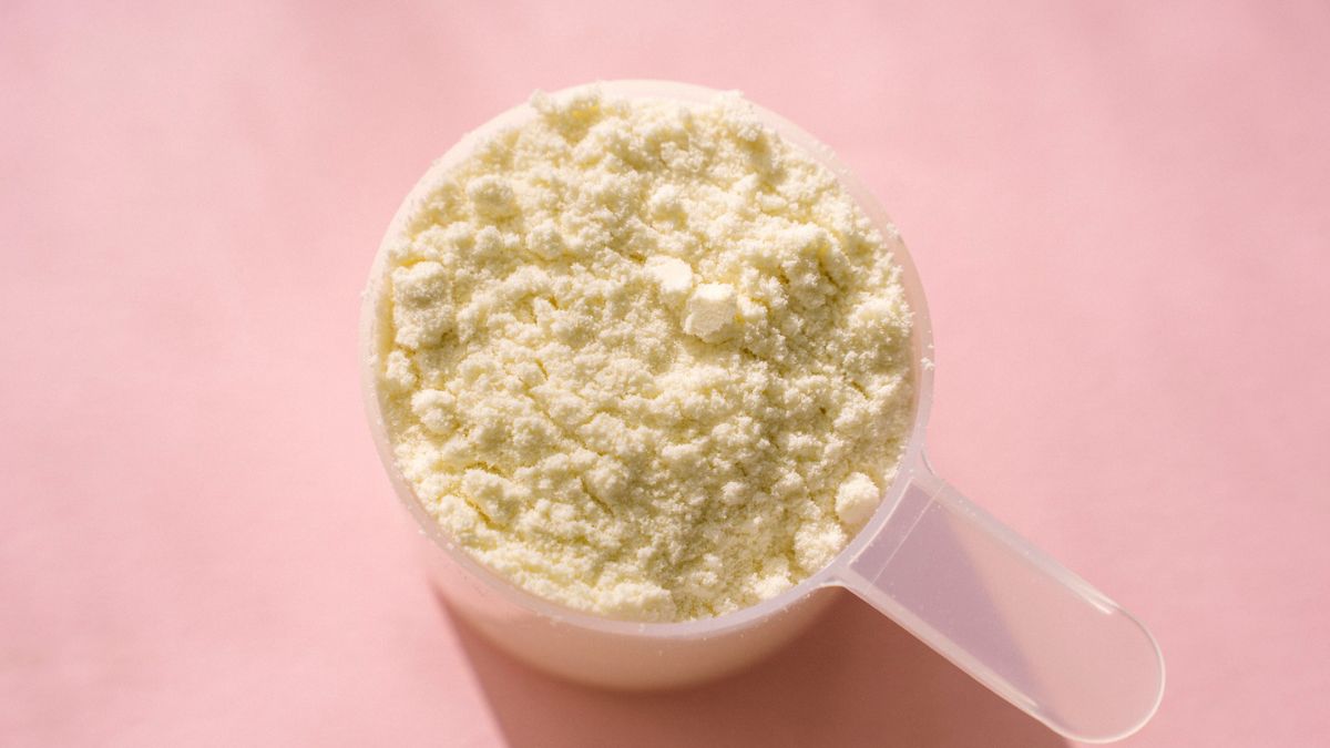 A scoop of protein powder on a pink background