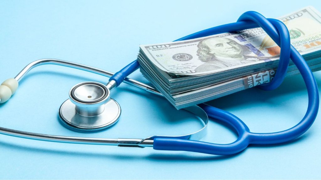 Stack of cash dollars and stethoscope on blue background. The concept of medical strechevka or expensive medicine, doctors salary