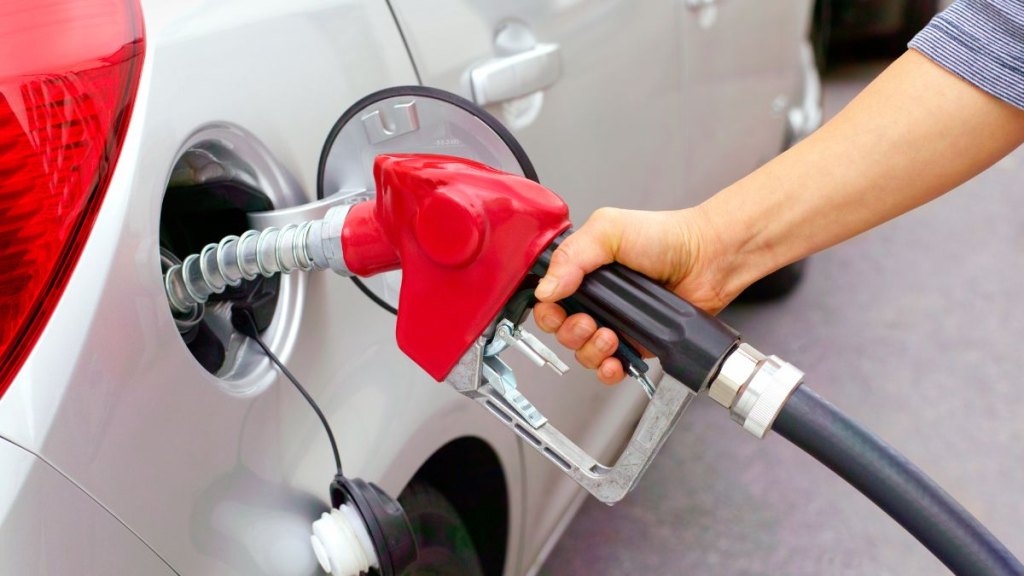 Woman filling car with leaded fuel in garage