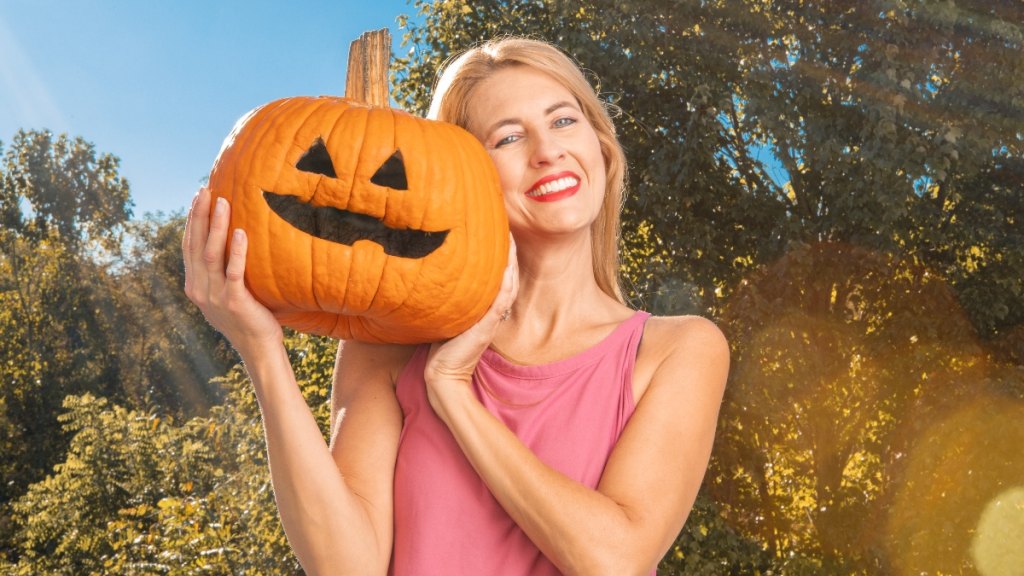 A woman holding a Jack-O'-Lantern in summer