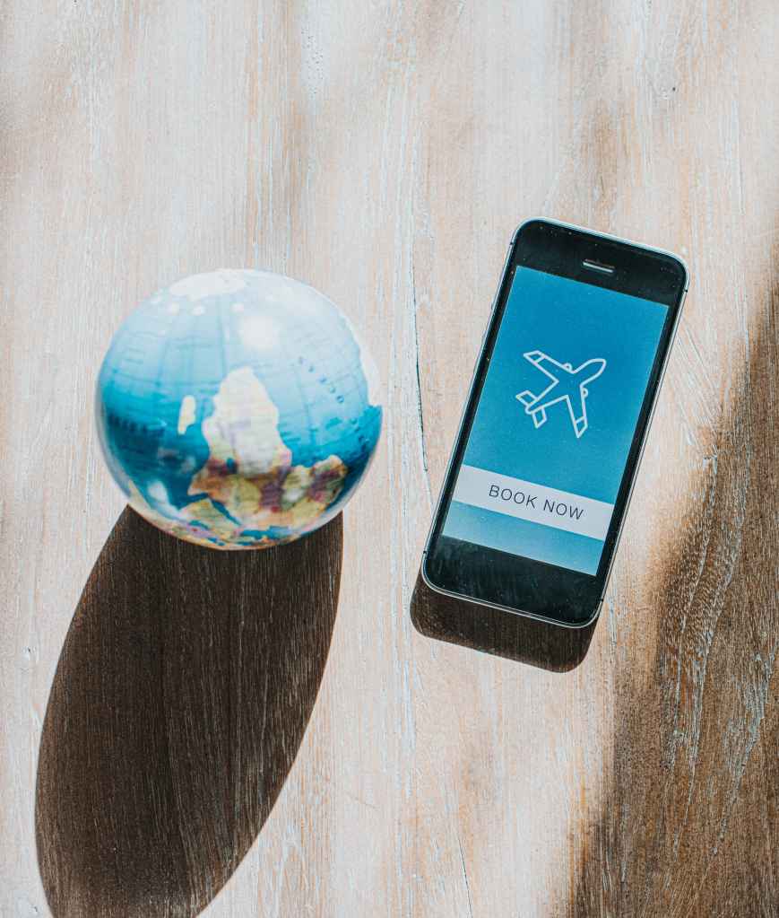 cellphone booking a flight next to a globe
