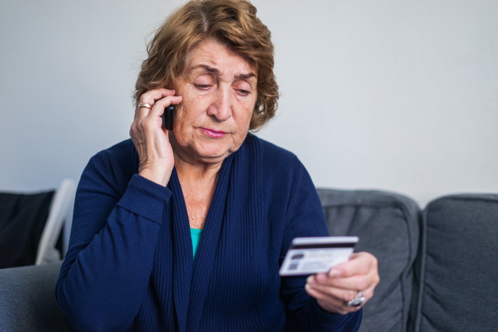 Senior woman using mobile phone while holding credit card