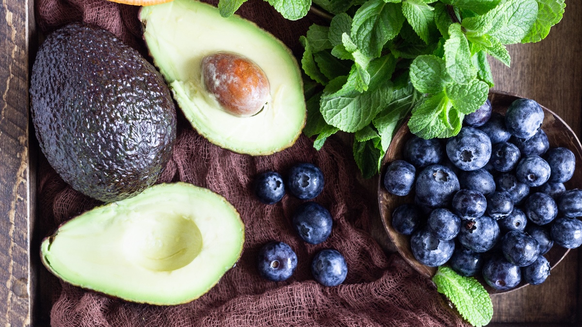 an overhead shot of sliced avocados and blueberries, fruits that are shown to be help prevent fatty liver disease