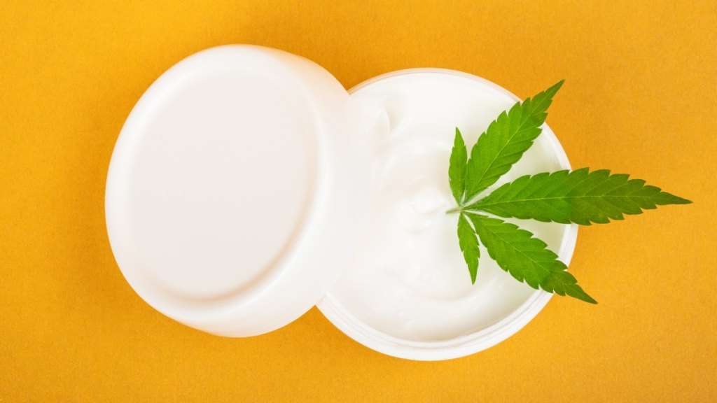 A CBD balm for pain relief with a CBD leaf against an orange background