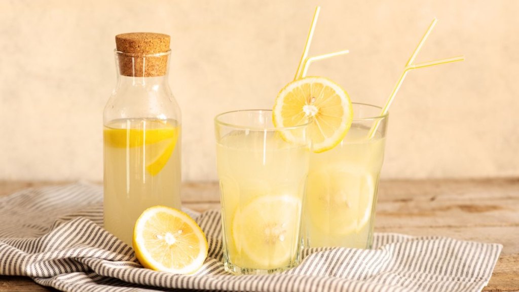 Jar of tasty fresh lemonade with lemons in background.