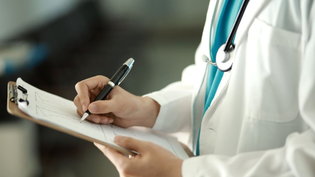 Doctor writing on clipboard