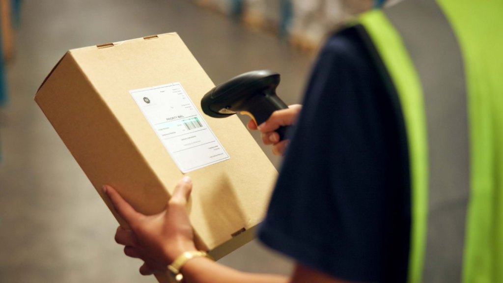 Employee, hands and box with scanner at warehouse for product, stocktaking and distribution. Manufacturing, person and barcode for delivery or package for supplier, supply chain and logistics