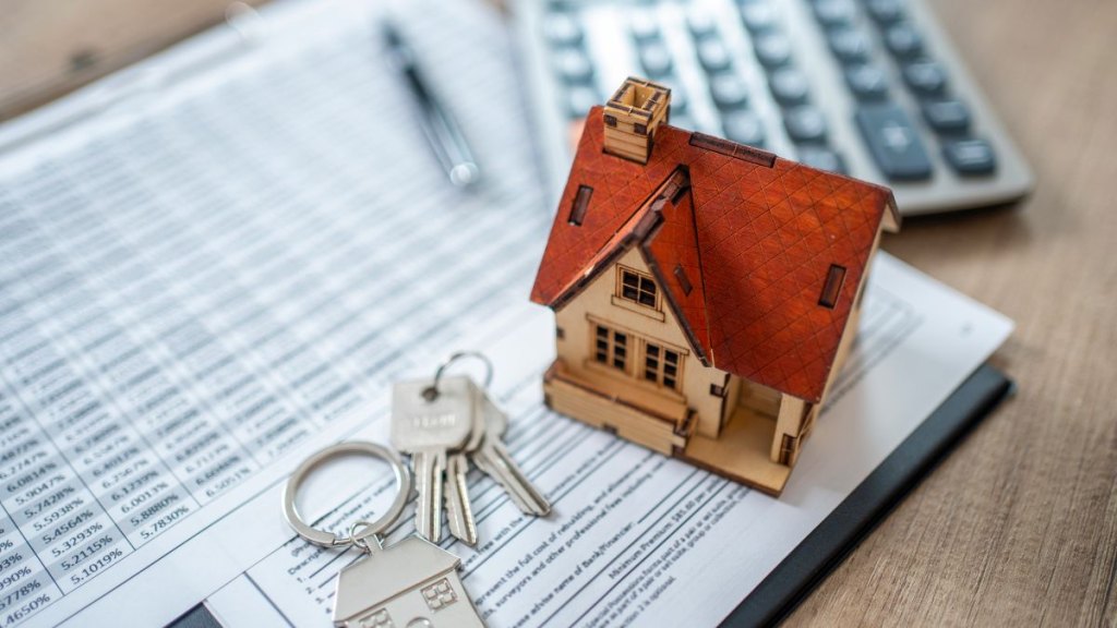 Shot of real estate broker work desk.Small house ,key and notebook.