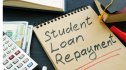 Student loan repayment sign, notepads, calculator and cash.