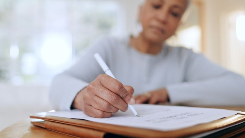 Senior woman, sign and writing with documents, paperwork and application for life insurance policy. Person, hand and checklist for compliance, investment or will in retirement with signature in home
