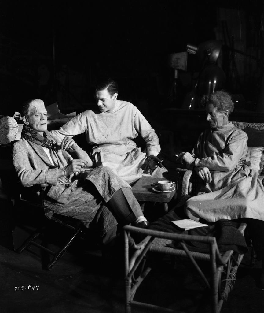 circa 1935: From left to right, actors Boris Karloff (1887 - 1969), Colin Clive (1898 - 1937) and Ernest Thesiger (1879 - 1961) pause for a cigarette break on the set of 'Bride of Frankenstein', directed by James Whale. They are still in costume as two mad scientists and a monster