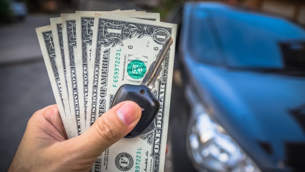 Close-Up Of Hand Holding Paper Currency With Key
