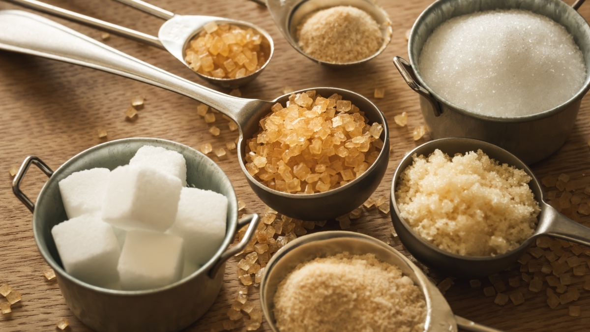 Measuring cups with various healthy sugar substitutes on a wooden table