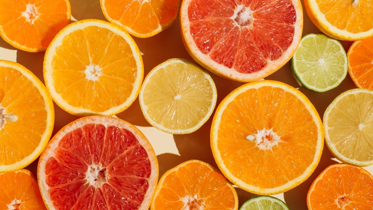 Various citrus fruits, which boost your immune system, sliced open against a pale peach background