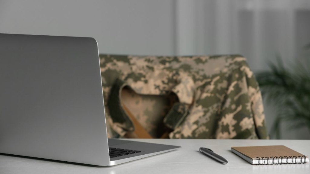 Notebook, laptop and pen on white table indoors. Military education