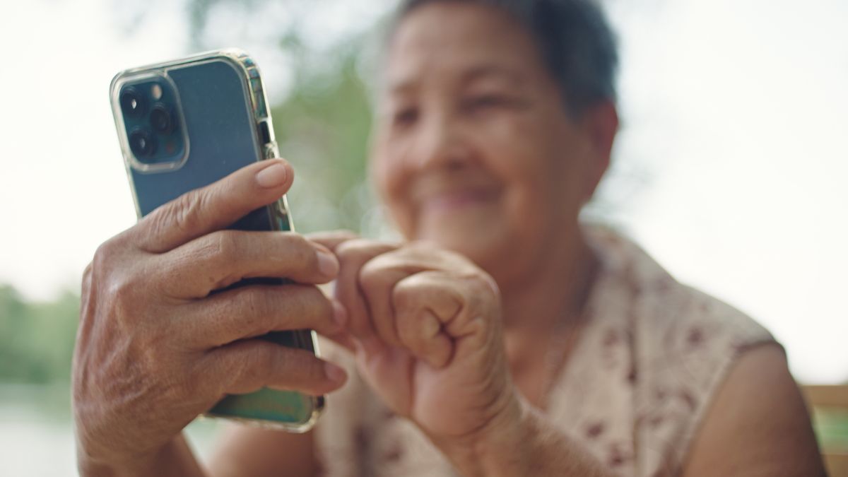 Asian senior woman using smartphone outdoors.