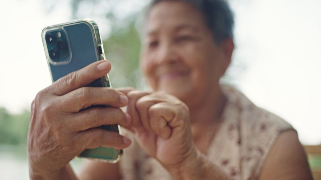 Asian senior woman using smartphone outdoors.