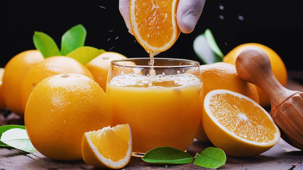 An orange being squeezed over a juice glass to help derive the benefits of hesperidin