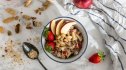 A bowl of oatmeal with high-fiber berries, nuts and apple slices on top