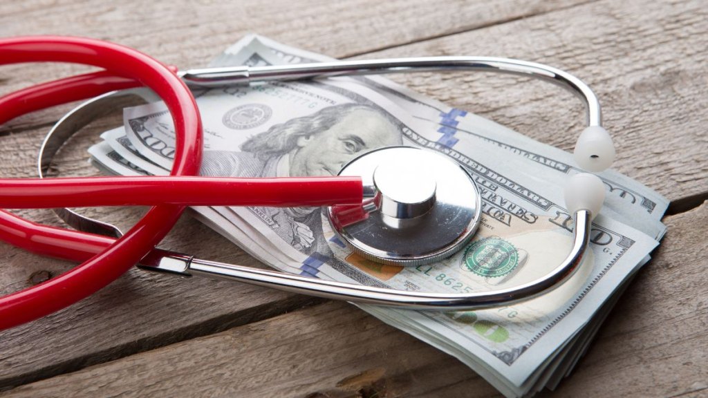 Health insurance concept - stethoscope over the money