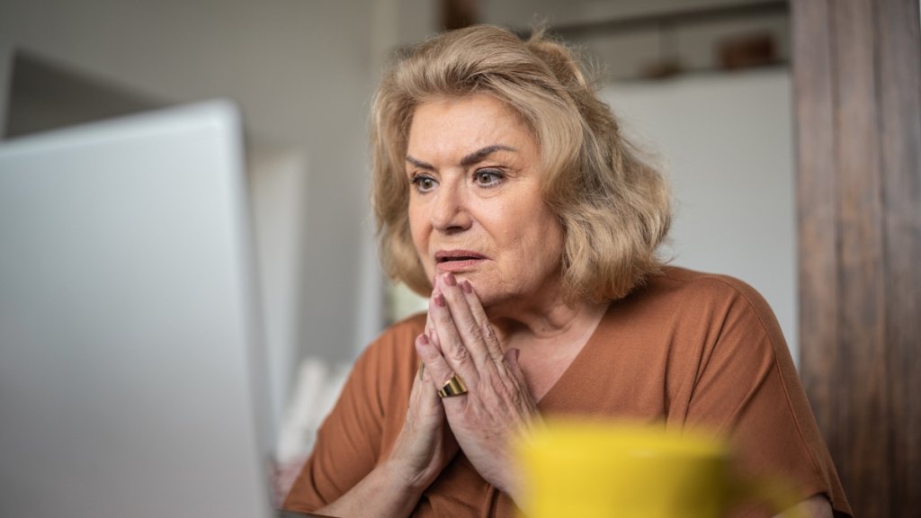 Senior woman looking worried while reviewing finances, representing the high cost of long-term care insurance.