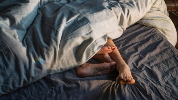 Couple's feet sticking out from under duvet in bed after having sex post-menopause