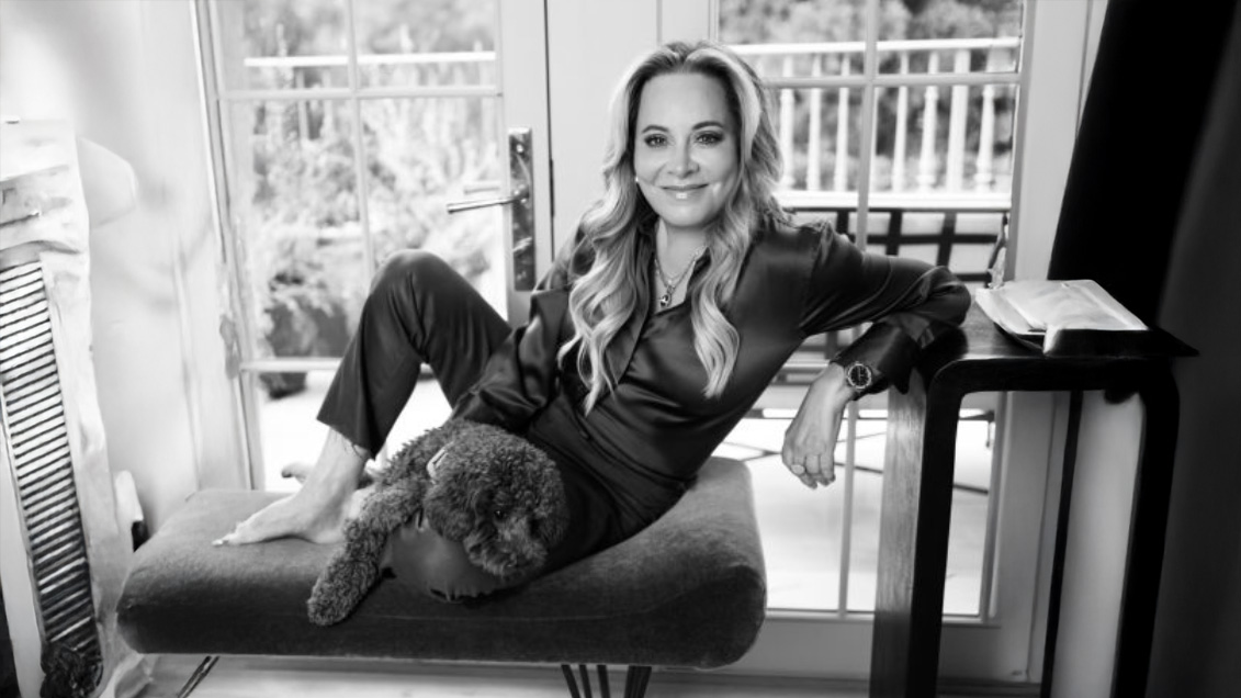 Black and white image of Theresa Bruno lounging on a chaise lounge with a small dog