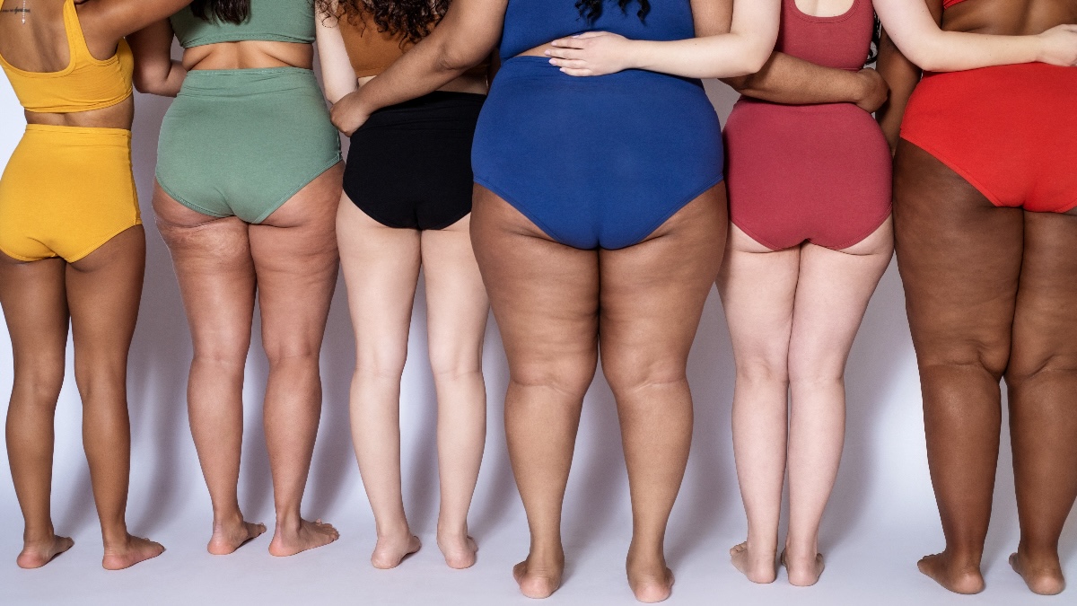 woman of different races, ages and health statuses proudly line up with their butts facing us