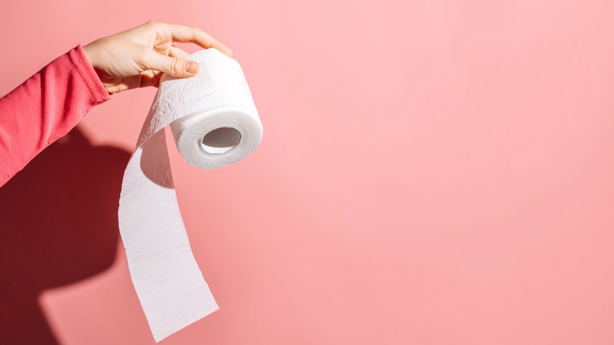 Woman's hand is seen holding a roll of toilet paper