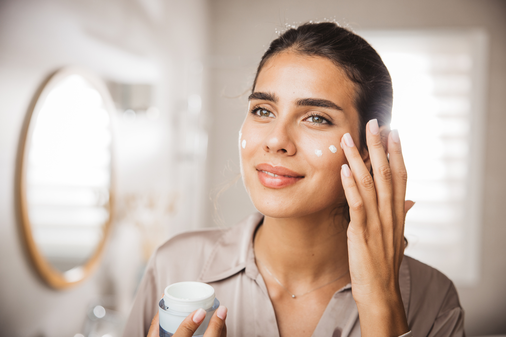 Woman applying skin cream to her face