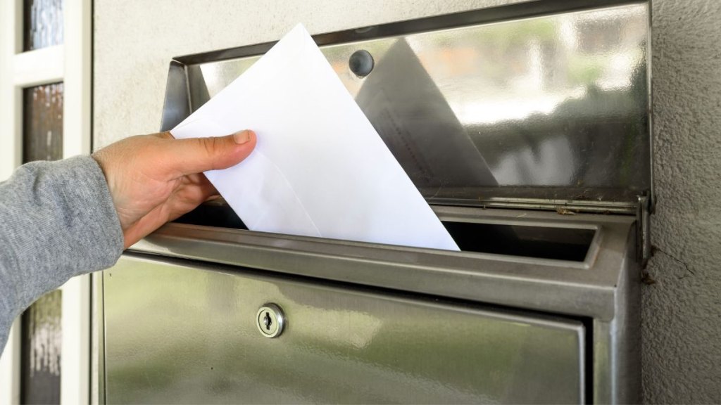 Hand putting mail in mailbox