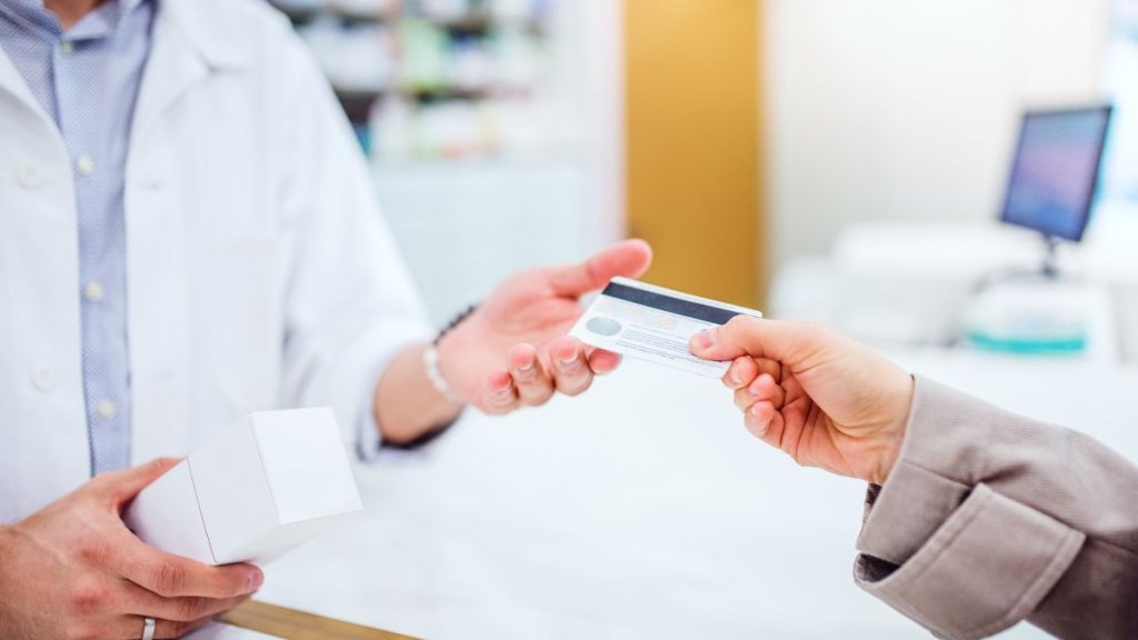 Unrecognizable customer giving a credit card to a male pharmacist