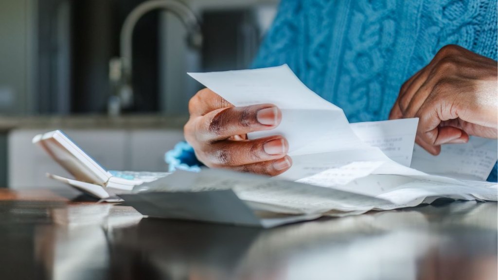 Woman Reviews Receipts at Kitchen Table