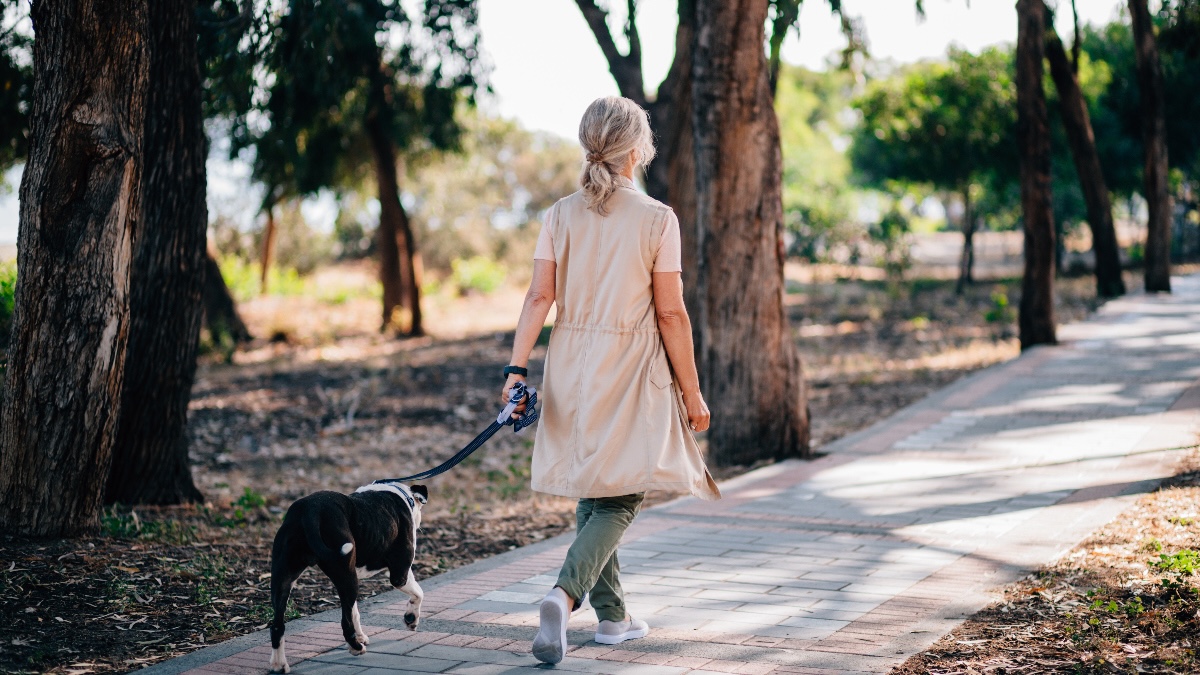 A woman walking her dog outdoors to reduce a post-meal blood sugar spike