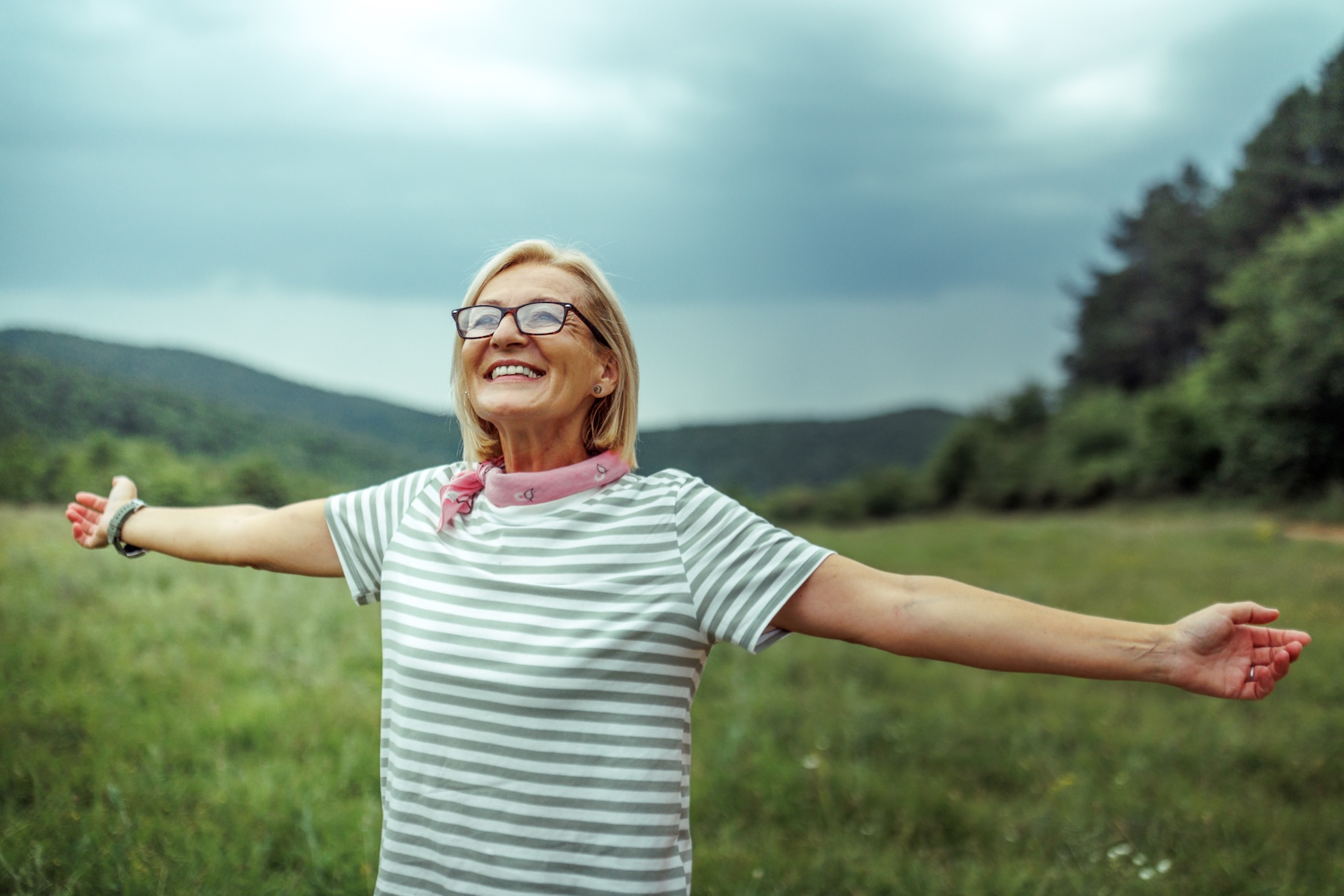 Smiling mature woman with arms outstretched enjoying her day in nature after learning how to increase oxytocin