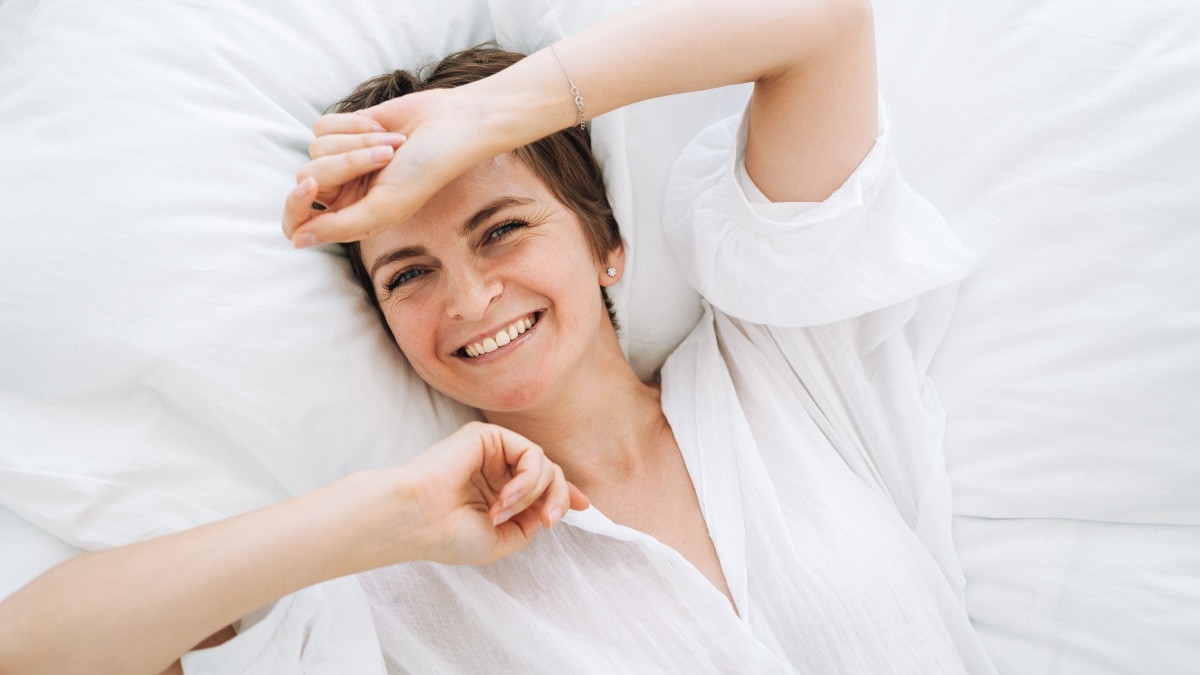Woman smiling in bed after discovering the best natural sleep apnea remedies