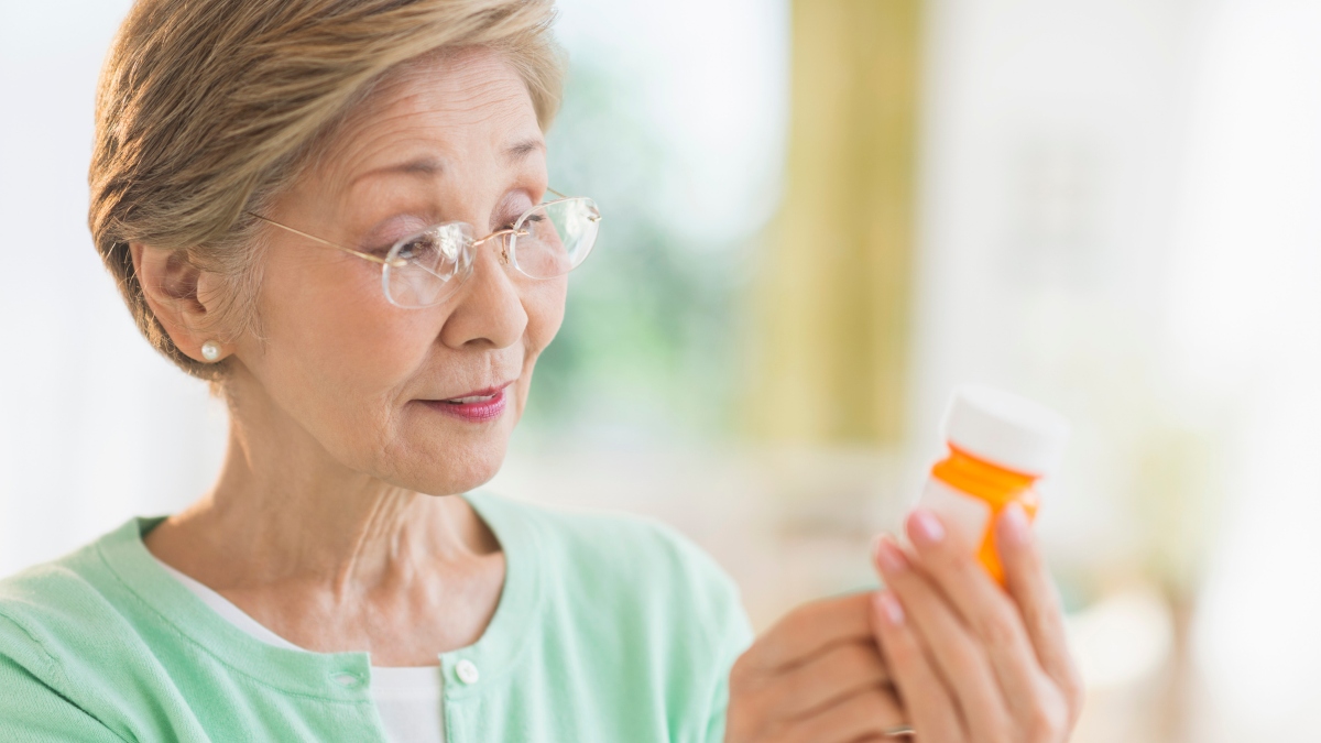 A woman looking at a statin bottle to read the side effects