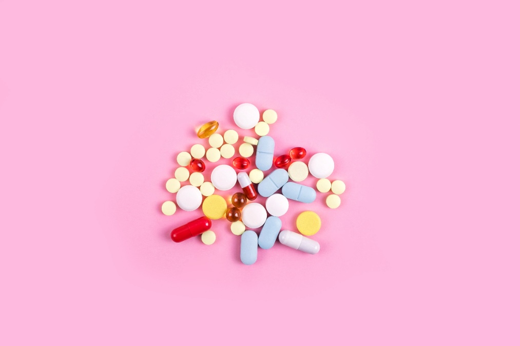 Multiple types of colorful skin health supplements against a pink background