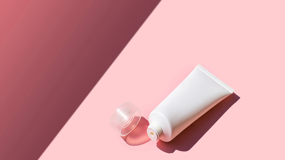White tube of testosterone cream against a pink background