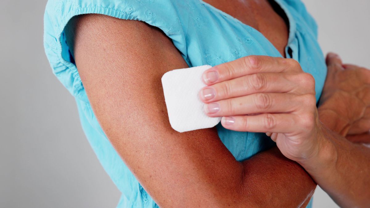 Close-up of a woman placing a vitamin patch on her arm