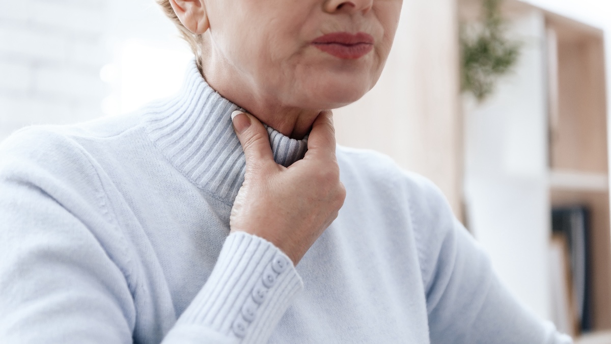 Close-up of a woman holding her throat and wondering why she can't swallow