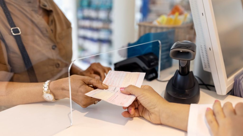 Close-up of a woman hand giving the medicine prescription to pharmacist in store