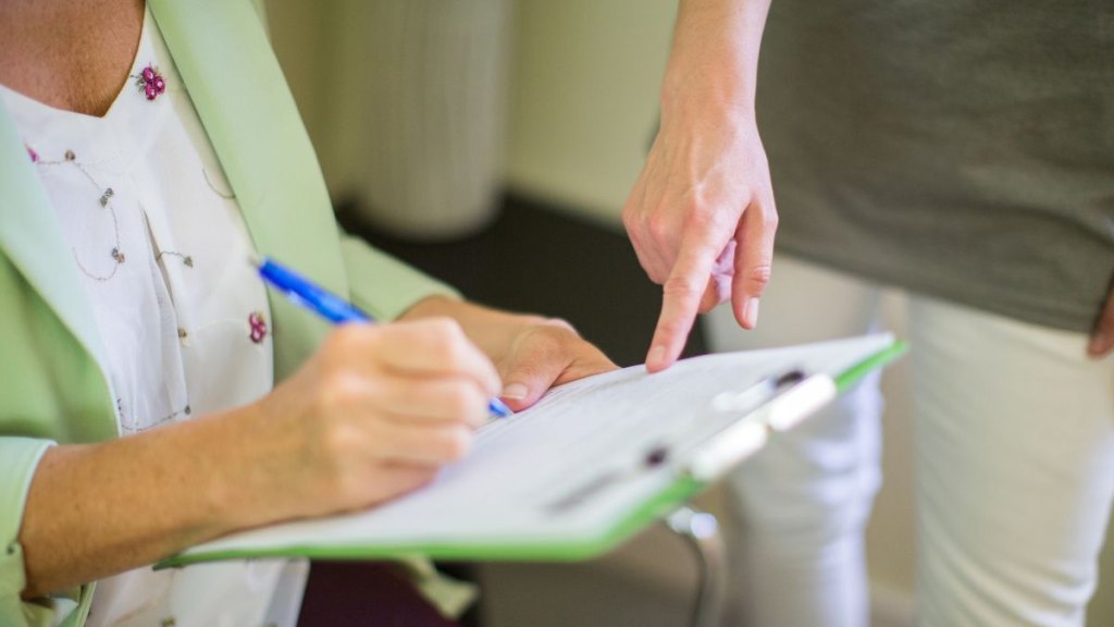 Female signing a form given to her by the doctor