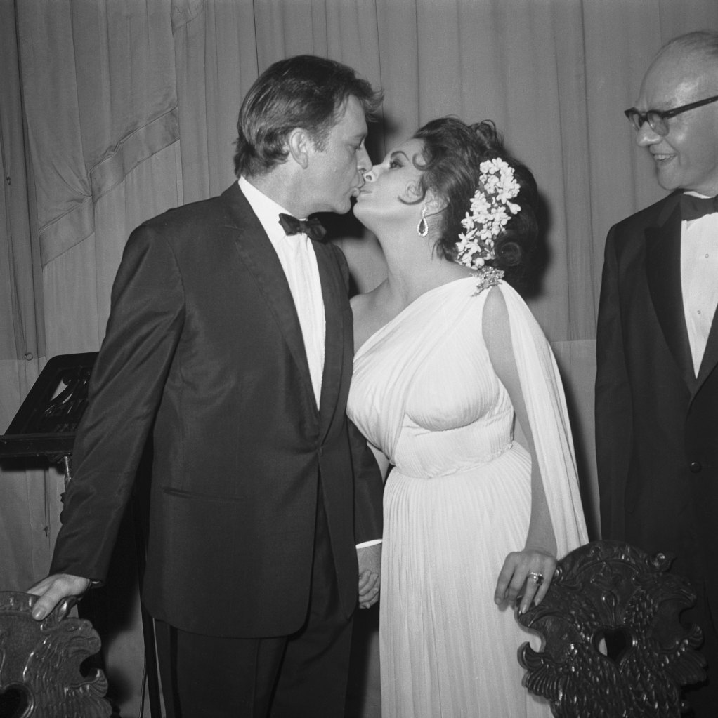 (Original Caption) 6/22/1964-New York: Actor Richard Burton kisses his beautiful actress-wife Elizabeth Taylor following their successful benefit performance of prose and poetry readings at the Lunt-Fontanne Theatre here, June 21st. Philip Burton, Burton's foster father, directed the show which was a benefit for the American Musical and Dramatic Academy.