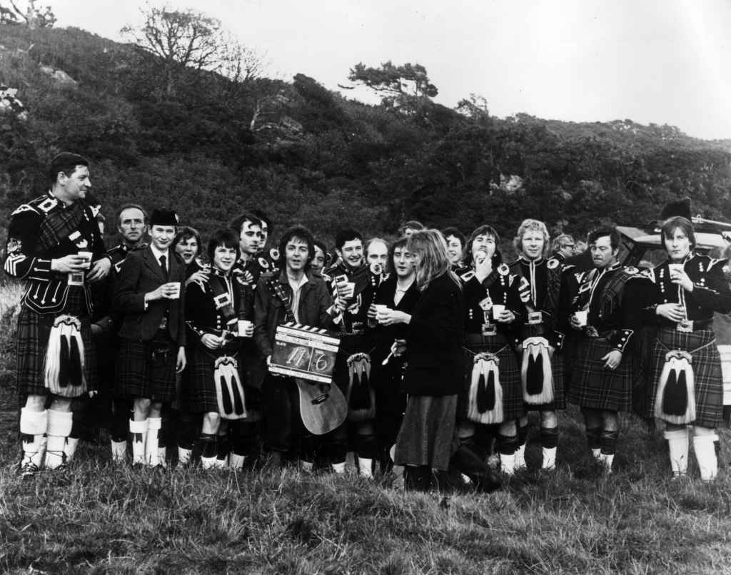 Paul and Linda McCartney with their Wings bandmate Denny Laine and the Campbeltown pipe band during the filming of the promotional video for the song 'Mull of Kintyre' in 1977